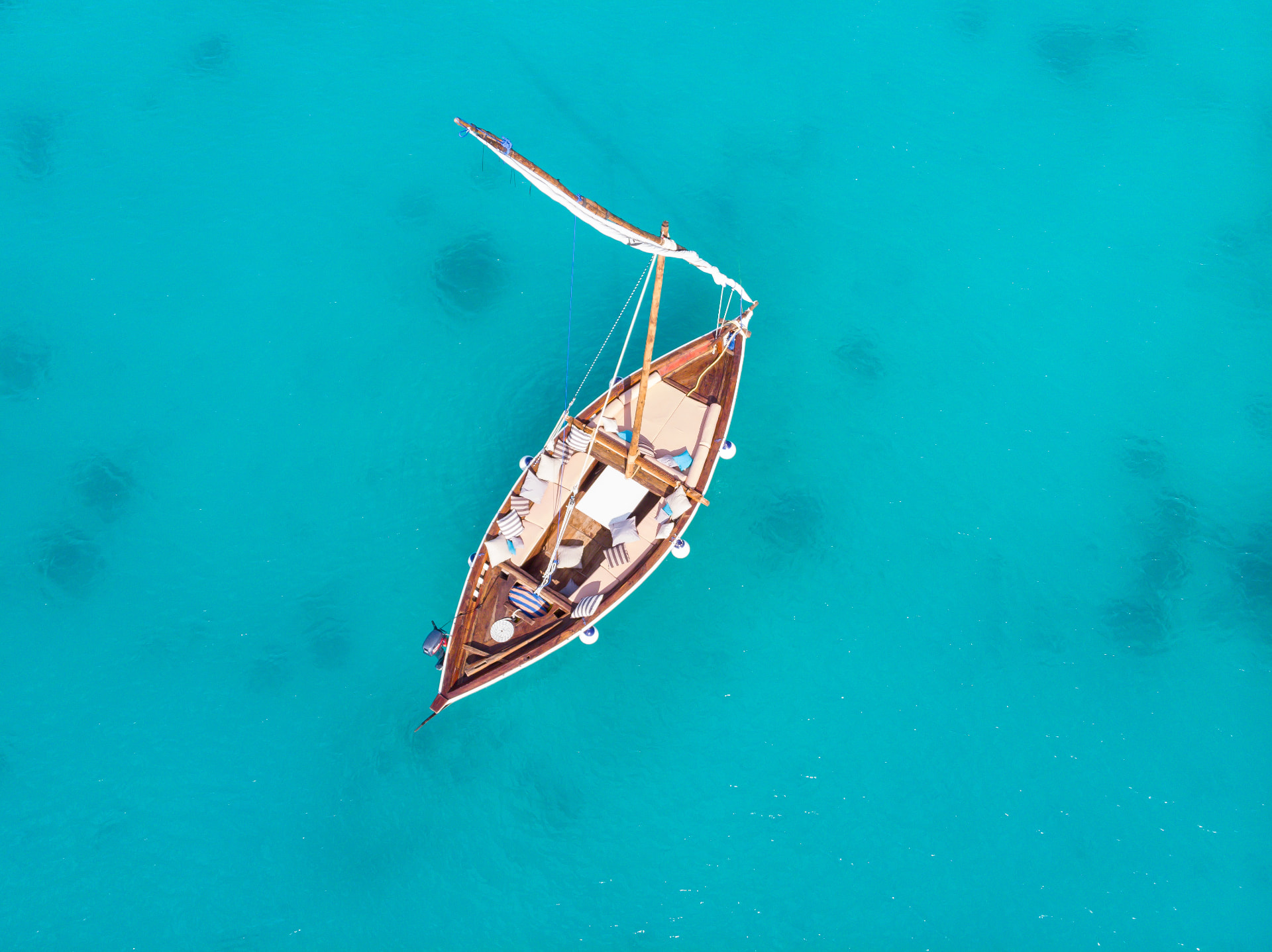 A dhow laid out with cushions, floating in turquoise water