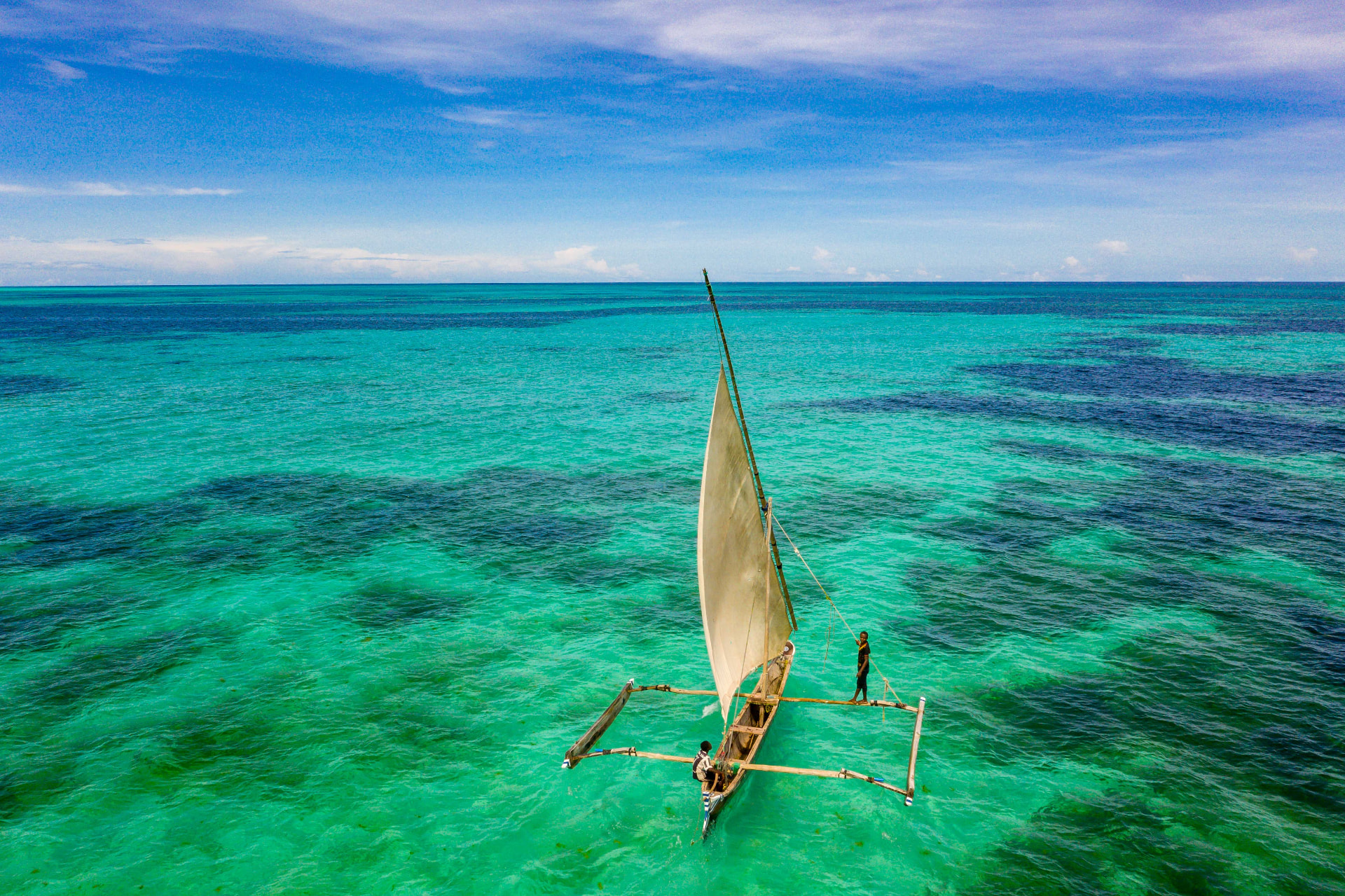 A traditional dhow under sail over the reef