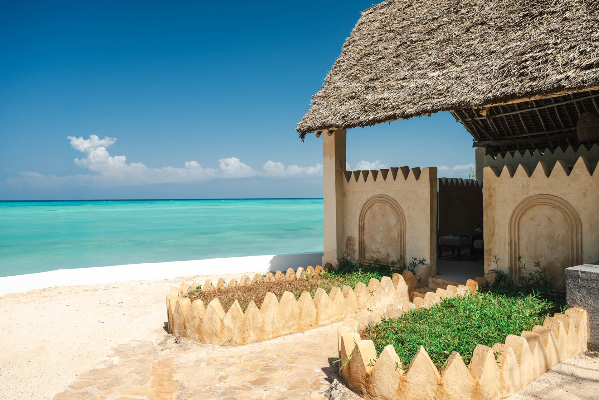 Beachfront spa cabana with a thatched roof