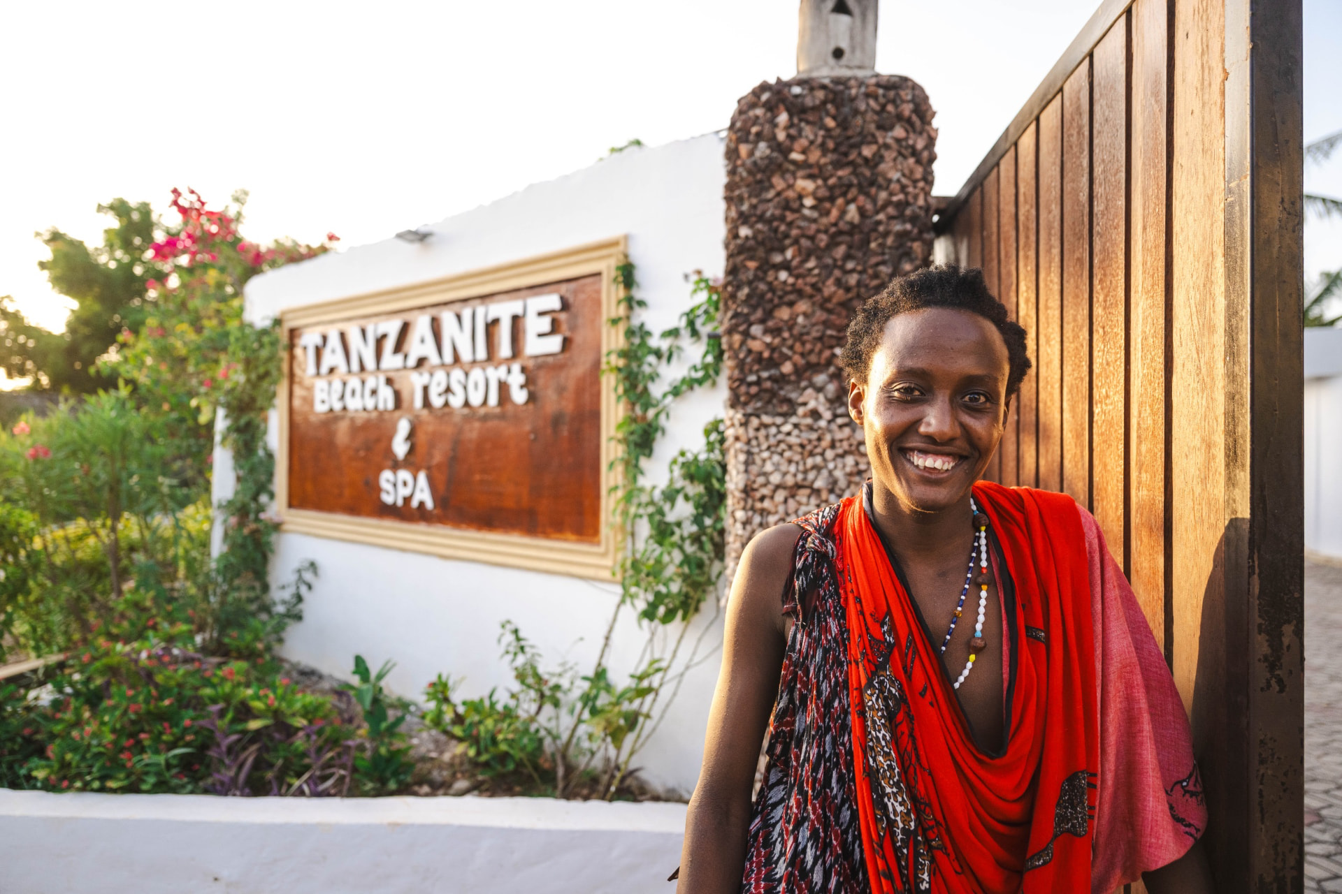 A host in traditional red at the resort gate